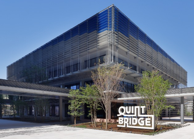 QUINTBRIDGEの建物の写真。建物名「QUINTBRIDGE」の立体文字のオブジェがビルの前に写っている。
